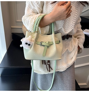 Detail of mint green woven texture handbag with detachable strap and plush monster charm