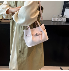 Detail of light pink woven texture crossbody bag shown being worn in daily life