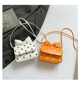 Close-up of stylish polka dot bow shoulder bags in white and orange synthetic leather