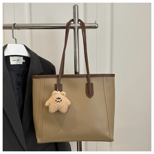 Detail of khaki tote bag with contrast stitching and a cute bear charm pendant