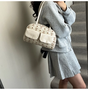 Detail of retro bear print shoulder bag featuring dual front flap pockets and cream PU leather