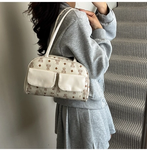 Detail of off-white shoulder bag with bear print and dual front pockets worn by a model