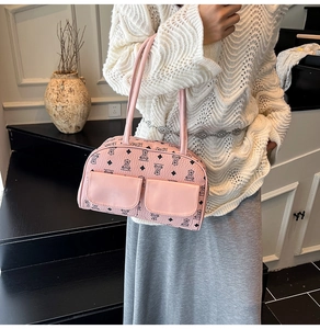 Detail of pink pebbled leather handbag featuring black bear prints and dual front pockets