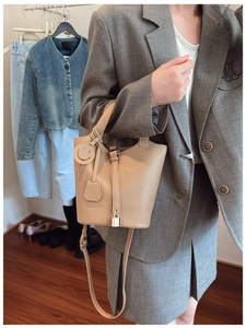 Detail of beige bucket bag with lychee grain leather, metal lock and smiley charm