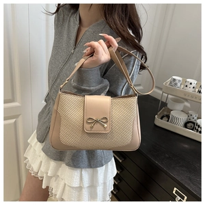 Detailed view of weave textured shoulder bag featuring an elegant gold bow clasp
