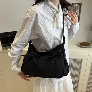 Chic black pleated nylon tote bag with decorative bows shown on a model in a modern room