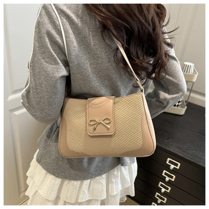 Detail showing the cream beige leather patchwork texture and golden bow buckle on the bag