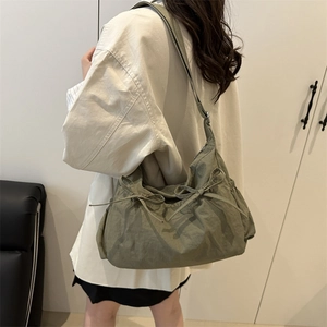 Borsa tote a tracolla plissettata verde muschio con fiocco, indossata da modella in interno