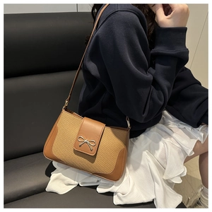 Detail of vintage woven shoulder bag with brown leather trim and silver bow buckle