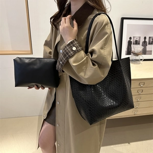 Black woven tote bag with matching leather pouch shown in a minimalist lifestyle setting