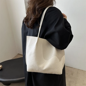 Minimalist white tote bag with woven texture shown on model in urban setting