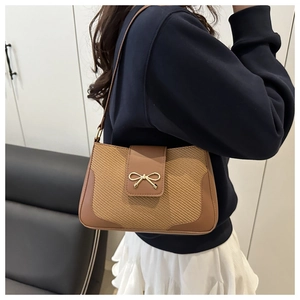 Detail of vintage brown leather and beige woven shoulder bag with golden bow buckle