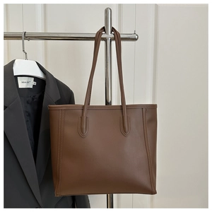 Detailed view of brown leather tote bag with fine stitching and slim dual straps