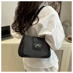 Detail of grey houndstooth shoulder bag with black leather and golden bow metal clasp