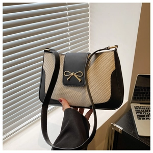 Close-up of woven cream texture with black leather trim and gold bow clasp detail