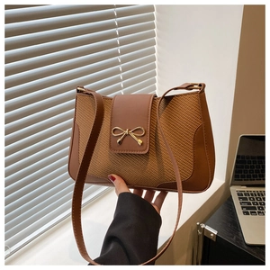 Detail of caramel brown woven texture and gold bow buckle on retro shoulder bag