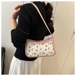 Elegante borsa sottobraccio crema con bordo rosa e stampe di ciliegie sulla modella