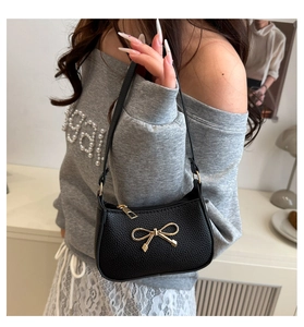 Detailed texture of black litchi leather underarm bag with gold bow accessory
