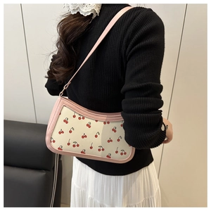 Dettaglio della borsa a spalla con stampa a ciliegia, bordo rosa e trama in pelle PU