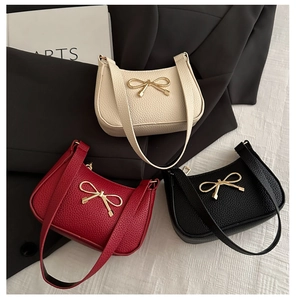 Detailed view of luxury bow-accented shoulder bags in cream white, red, and black leather