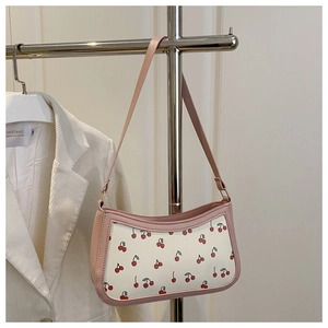 Dettaglio della borsa baguette con stampa ciliegia rosa e bianca su giacca bianca