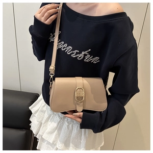 Vue détaillée du sac beige avec boucle dorée ovale et fermeture en métal texturé