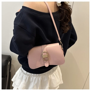 Side view of soft pink shoulder bag with large metal buckle worn by a model