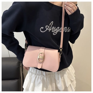 Gros plan d'un sac à bandoulière en cuir rose avec boucle décorative en métal doré