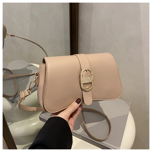 Close-up of the vintage gold textured oval buckle on a beige leather shoulder bag
