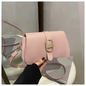 Close-up of pink shoulder bag featuring a sleek gold oval buckle and premium leather texture