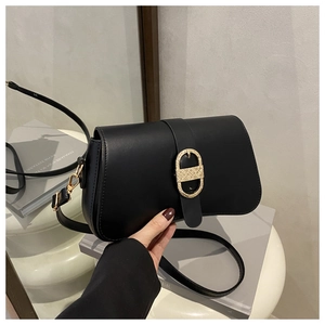 Detail of black matte leather shoulder bag with engraved oval gold metal buckle closure