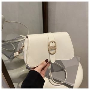 Détail d'un sac à main minimaliste en cuir crème avec boucle ronde en métal doré brillant