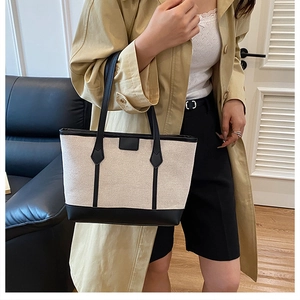 Détail du sac cabas en toile avec garniture en cuir noir porté sur un trench-coat