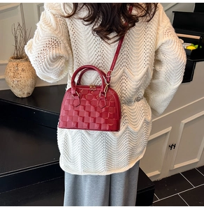 Rote glänzende Muscheltasche mit Schachbrettmuster an Model in eleganter Umgebung