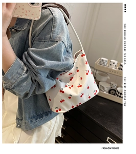 Detail of lady underarm bag with red cherry prints and white shoulder straps