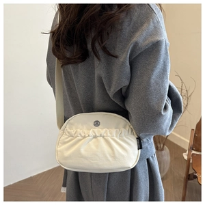 Detail of off-white pleated canvas crossbody bag with metal logo and fabric strap