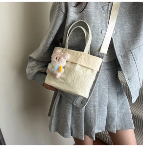 Détail du sac seau en tissu Oxford crème avec texture froissée et breloque ours mignon