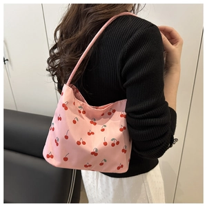 Détail d'un sac porté épaule rose avec motif cerises et bandoulière en tissu