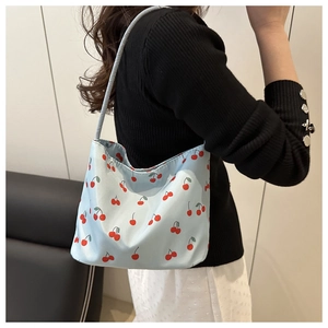 Détail du sac bandoulière en nylon bleu clair avec motif imprimé cerises rouges