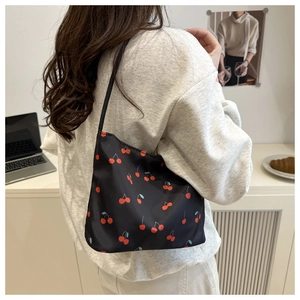 Detailed view of black bucket bag with red cherry prints shown on shoulder