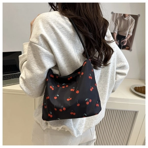 Shoulder bag featuring red cherry prints worn by a model in a cozy indoor setting