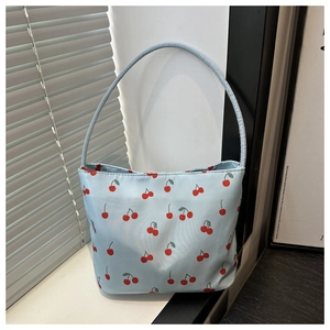 Detailed view of light blue nylon bucket bag featuring vibrant red cherry prints