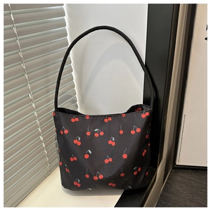 Detail of waterproof nylon bucket bag featuring vibrant red cherry print and slim strap