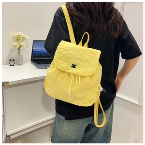 Detail of yellow drawstring backpack with crinkled texture and cute cat logo on back