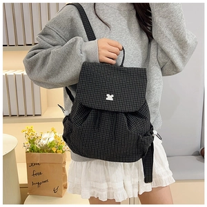 Detail of black and white checkered drawstring backpack with flap closure and puzzle logo