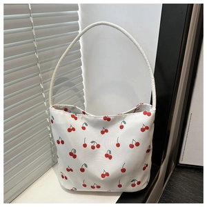 Gros plan d'un sac seau en nylon blanc avec motifs de cerises rouges et bandoulière longue