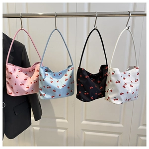 Detail view of four cherry print tote bags in pink, light blue, black, and white colors