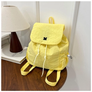 Detailed close-up of a bright yellow nylon drawstring backpack on a wooden table