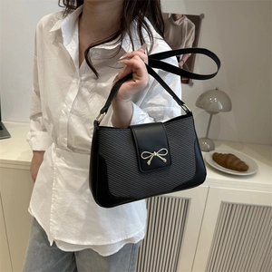 Retro black shoulder bag with bow detail and textured splicing shown on a model