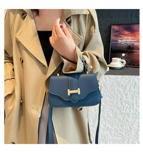 Detail of blue textured leather handbag with gold H buckle on beige trench coat